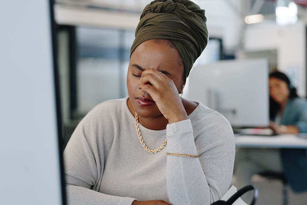 Image shows employee sat at desk at work struggling with burnout